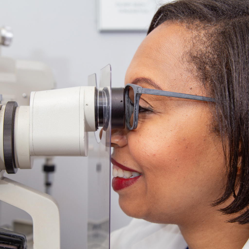 African American female doctor looking performing eye exam